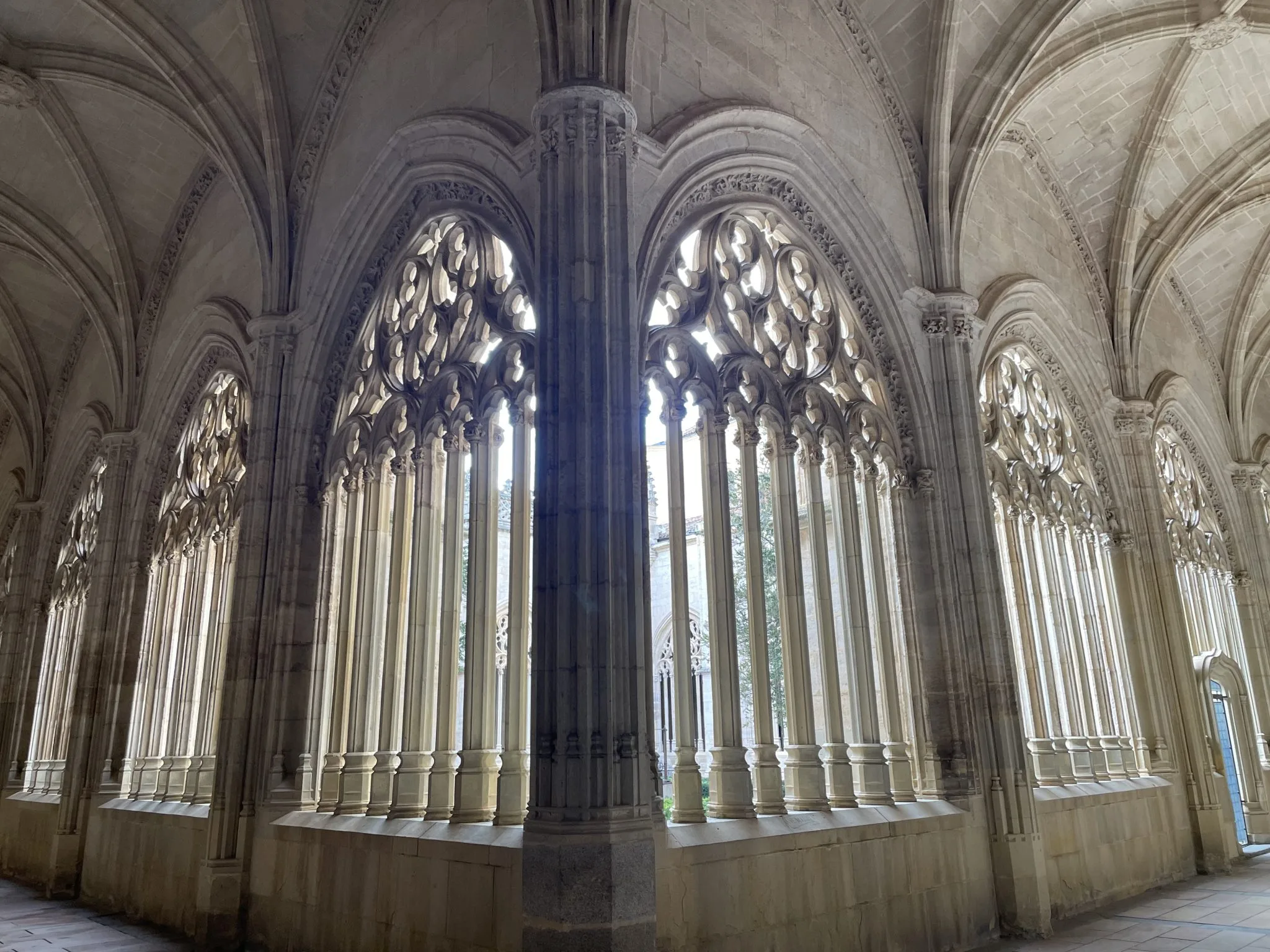 A vaulted stone cloister lit through tall Gothic windows